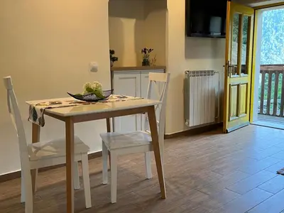 a table and chairs in a kitchen with a television at Apartment Abinkar in Tolmin
