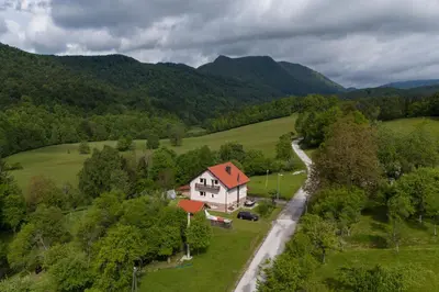 a house with a red roof in a green field at Deer Land Photo Apartment in Kočevska Reka