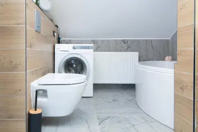 a bathroom with a toilet and a washing machine at Deer Land Photo Apartment in Kočevska Reka