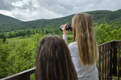 two girls taking a picture of the mountains with a camera at Deer Land Photo Apartment in Kočevska Reka