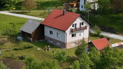 a house with two children standing in front of it at Deer Land Photo Apartment in Kočevska Reka