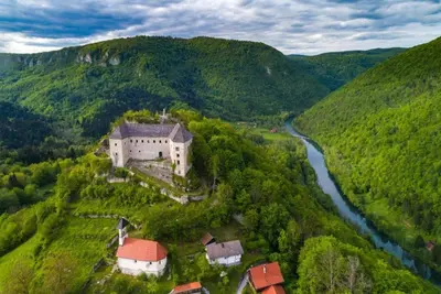 an aerial view of a building on a hill next to a river at Deer Land Photo Apartment in Kočevska Reka