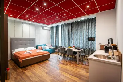 a bedroom with a bed and a table and a kitchen at Oxford Apartments in Ljubljana