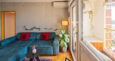 a living room with a green couch and red pillows at The Zen Apartment in Ljubljana