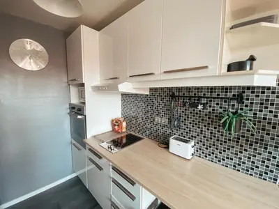 a kitchen with white cabinets and a wooden counter top at Charming Apartment Siska in Ljubljana
