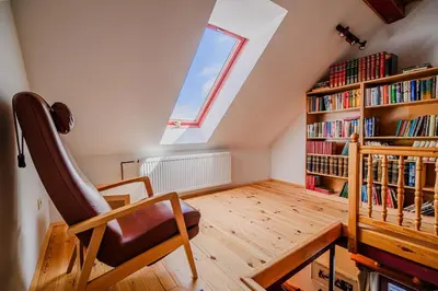 a attic room with a book shelf and a chair at Kaval Home with Free Onsite Wellness in Dravograd
