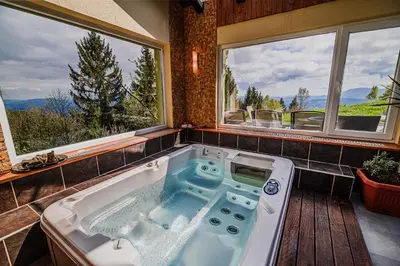 a large bath tub in a room with windows at Kaval Home with Free Onsite Wellness in Dravograd
