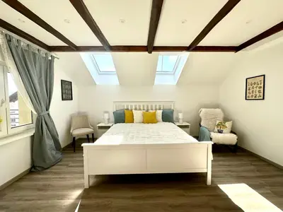 a bedroom with a white bed and two chairs at Sunny 3-room apartment with a terrace in Ljubljana