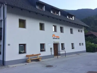 a white building with a bench in front of it at Apartmaji in sobe Tina in Kranjska Gora