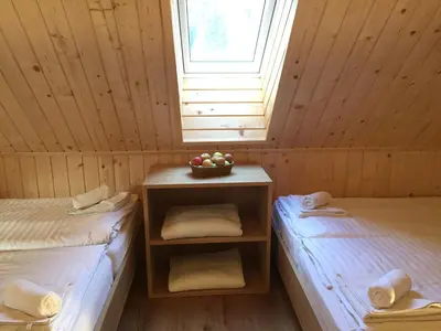 a room with two beds and a bowl of fruit on a table at Apartmaji in sobe Tina in Kranjska Gora
