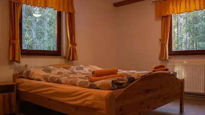 a bed in a bedroom with two windows at Digital Detox Chalet Pokljuka in Goreljek