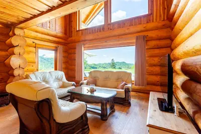 a living room with couches and a tv in a log cabin at Villa Harmonia Private Jacuzzi and Pool Retreat near Rogaška in Rogatec
