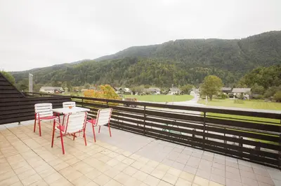 a table and chairs on a balcony with a view of a mountain at Sobe Krona in Radovljica