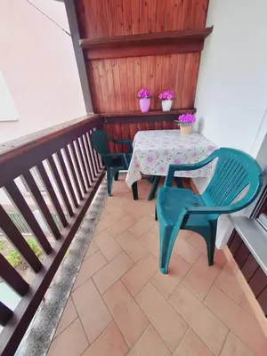 a table and chairs on a balcony with two flowers at Apartma Ferjan in Žaga