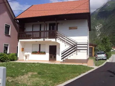 a white house with a balcony and a yard at Apartma Ferjan in Žaga