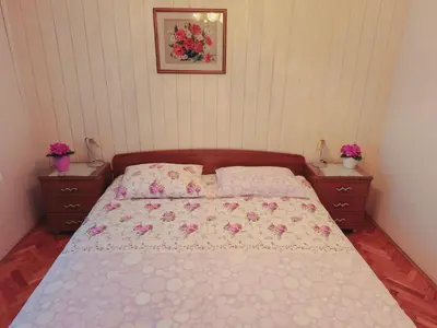 a bedroom with a bed and two nightstands with flowers on it at Apartma Ferjan in Žaga