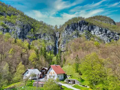 a village in the mountains with a waterfall at Apartma Pr'kovač in Bohinjska Bistrica