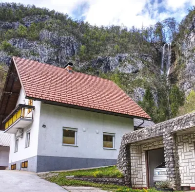 a white house with a red roof in front of a mountain at Apartma Pr'kovač in Bohinjska Bistrica
