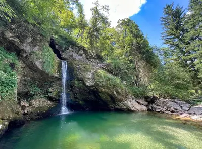 a waterfall in a pool of water next to a rock wall at Apartma Pr'kovač in Bohinjska Bistrica