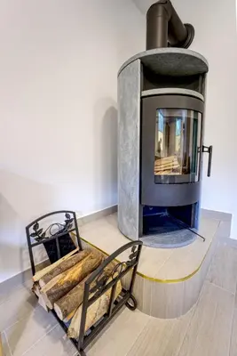 a wood fired oven in a room with a chair at Apartma Pr'kovač in Bohinjska Bistrica