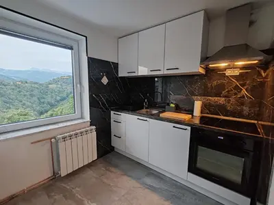 a kitchen with white cabinets and a large window at Apartments Stella Vittoria in Ročinj