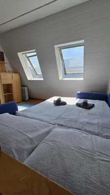 a large bed in a room with two windows at Apartma Lisjak in Bovec