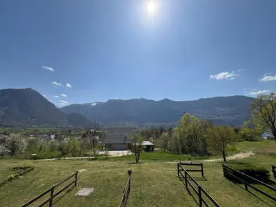 a field with a fence and mountains in the background at Apartma Lisjak in Bovec
