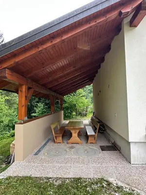 a patio with a table and benches under a roof at Krtajse in Slappe dʼIdria