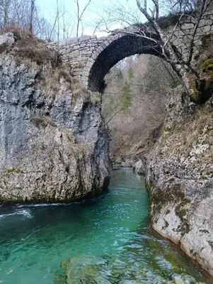 a stone bridge over a river with green water at Krtajse in Slappe dʼIdria