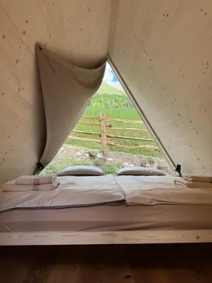 a bed in a tent with a view of a field at Glamping Kamp Triglav in Soča