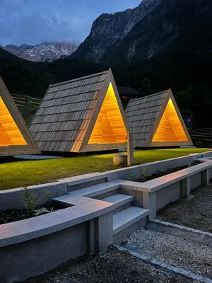three triangular buildings with orange and yellow roofs at Glamping Kamp Triglav in Soča