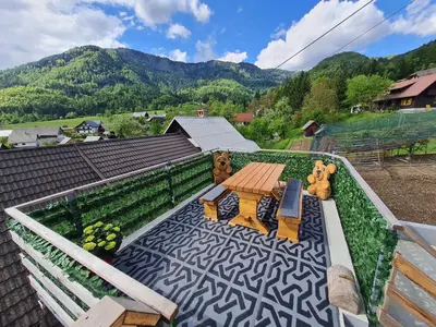 a patio with a table and benches on a roof at Apartma Grm in Bohinj