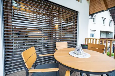 a table and chairs with a large window with blinds at Cozy House Claudia in Žirovnica