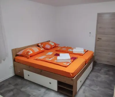 a bed with orange blankets and pillows on it at Apartment One2one in Bovec
