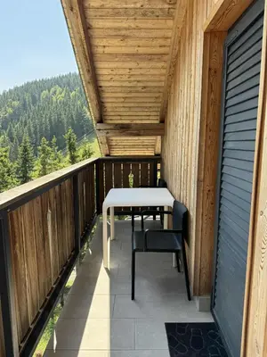 a wooden balcony with a table and chairs on it at OTTA Apartments Golte C1 in Mozirje