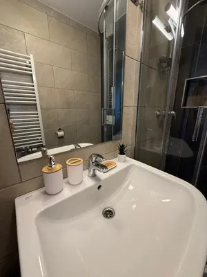 a bathroom sink with two cups on top of it at OTTA Apartments Golte C1 in Mozirje