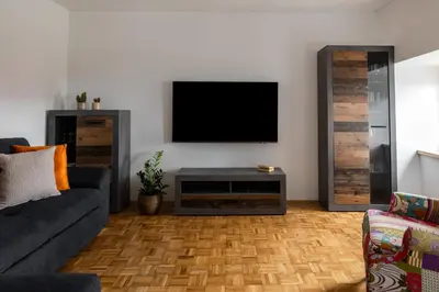 a living room with a couch and a television on a wall at Wellba Holiday Home Otlica in Ajdovščina