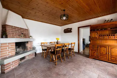 a dining room with a fireplace and a table and chairs at Wellba Holiday Home Otlica in Ajdovščina