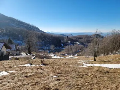 a field with snow and trees on a hill at Wellba Holiday Home Otlica in Ajdovščina