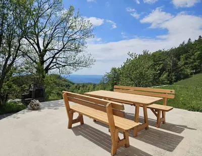 two wooden benches sitting next to a picnic table at Wellba Holiday Home Otlica in Ajdovščina