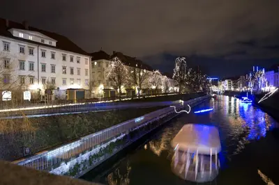 a boat on a river in a city at night at Zois Apartments in Ljubljana