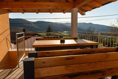 a wooden table on a deck with a view at Apartments Pr' Užlejbvih in Podnanos
