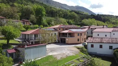 a small village with houses and a mountain at Apartments Pr' Užlejbvih in Podnanos