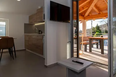 a kitchen with a television and a dining room with a table at Apartments Pr' Užlejbvih in Podnanos