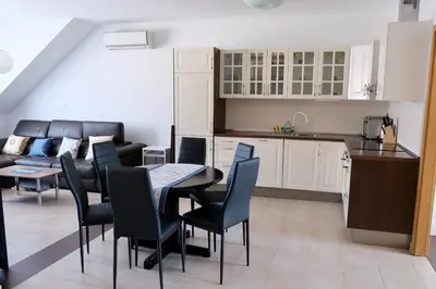 a kitchen and a living room with a table and chairs at Apartma z dvema spalnicama in balkonom in Maribor