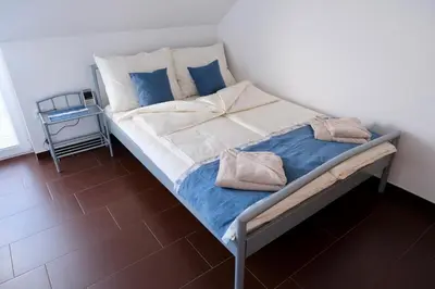 a bed with blue and white pillows on it at Apartma z dvema spalnicama in balkonom in Maribor