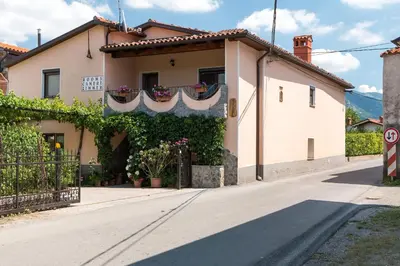 a white house with flowers on a street at APARTMA in SOBE PILIH in Vipava