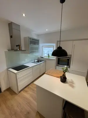 a kitchen with white cabinets and a black pendant light at Valle Apartment City Center in Ljubljana