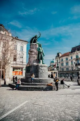 a statue in a square with people sitting around it at Valle Apartment City Center in Ljubljana