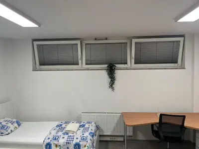 a bedroom with two windows and a desk and a bed at New Modern App in Ljubljana